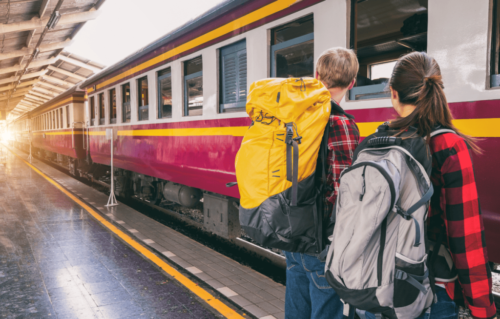 un train rouge, jaune et blanc avec deux adolescents au premier plan